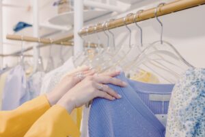 Hands arranging clothes on garment hangers